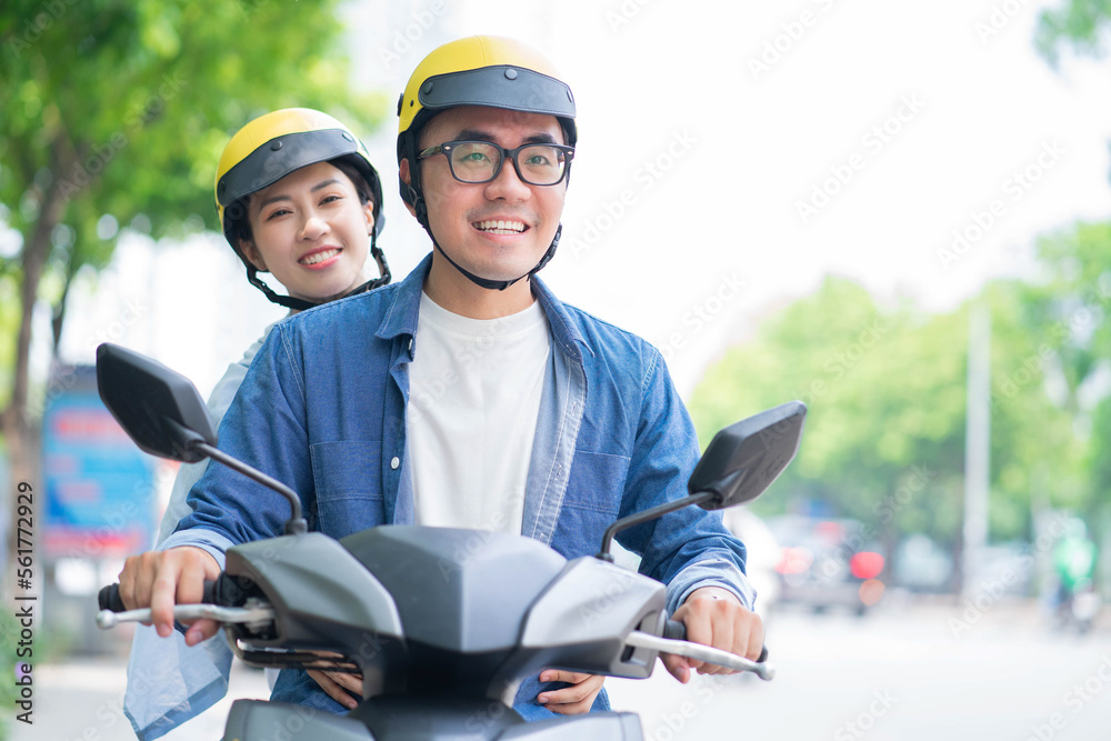 一对年轻的亚洲夫妇驾驶摩托车的照片