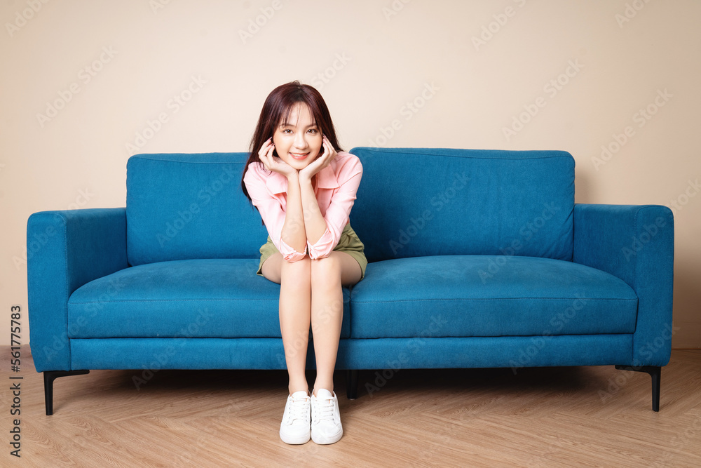 Image of young Asian woman sitting on sofa