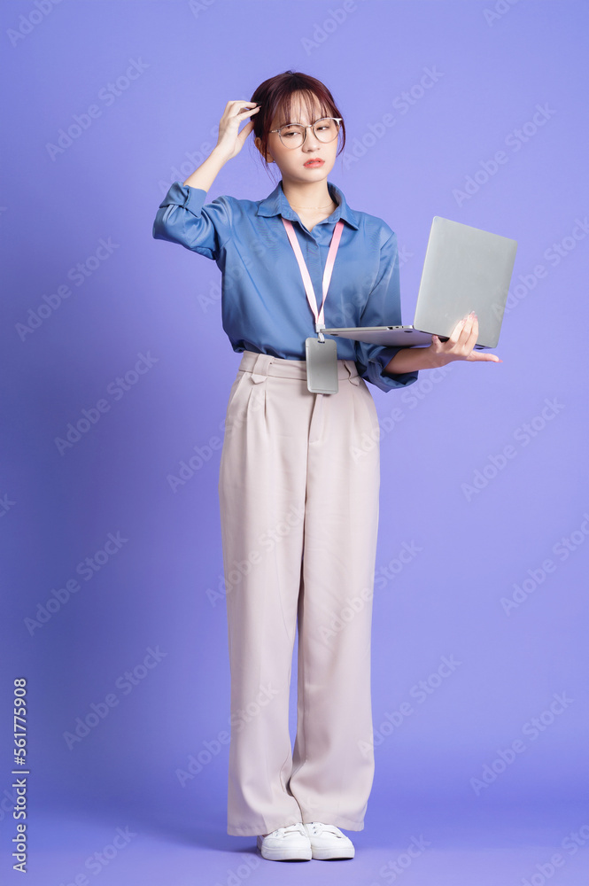 Photo of young Asian businesswoman holding laptop on background