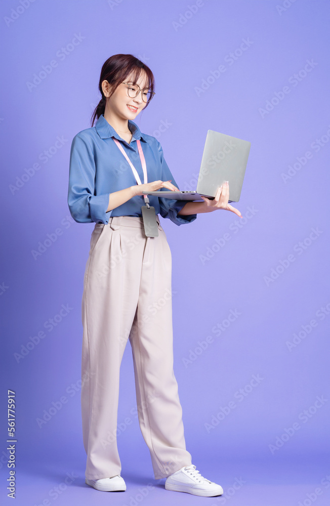 Photo of young Asian businesswoman holding laptop on background