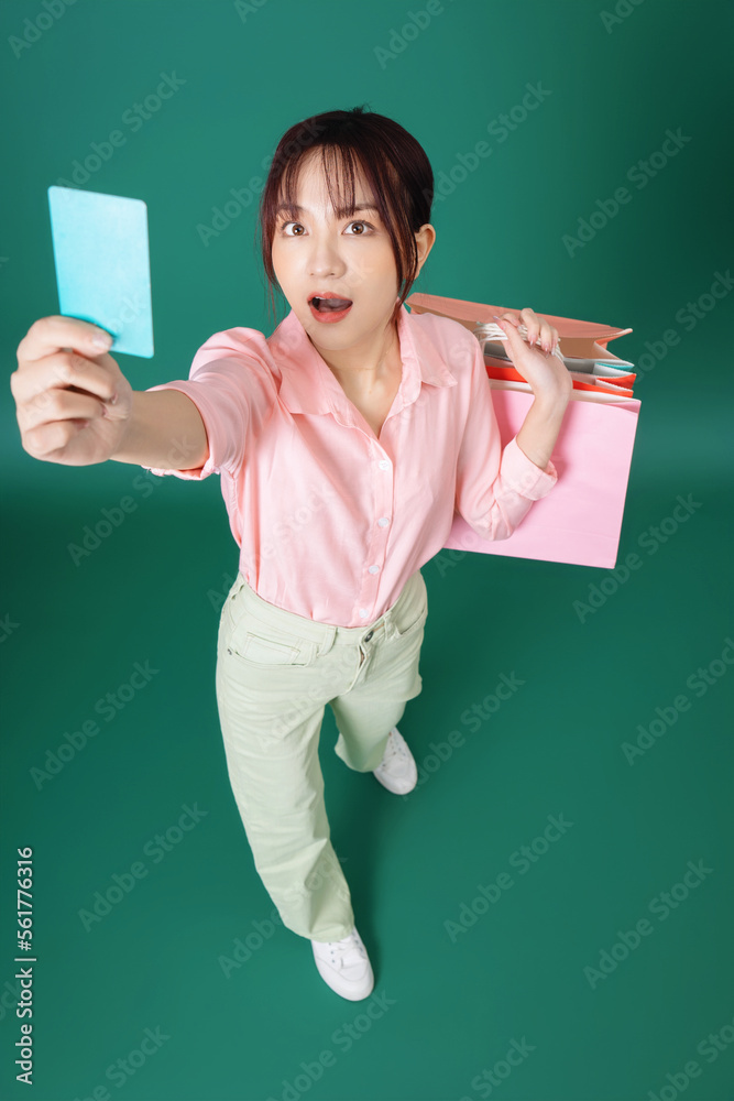 Image of young Asian girl holding shopping bag on background