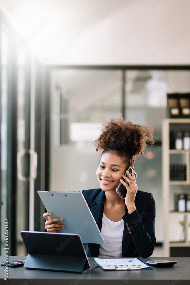 Business Africa woman Talking on the phone and using a laptop with a smile while sitting at modern o