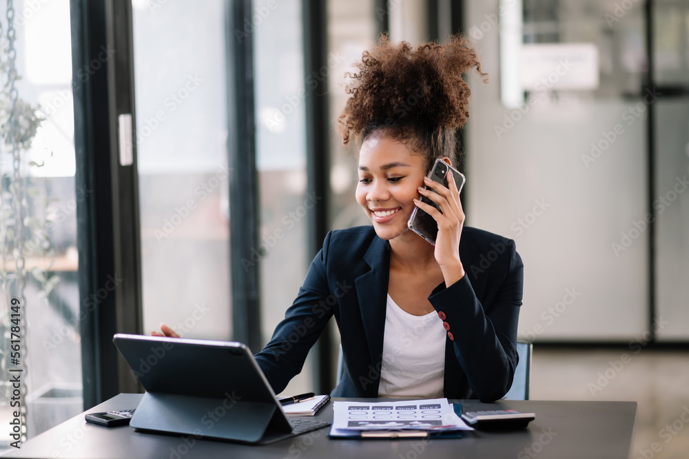 Business Africa woman Talking on the phone and using a laptop with a smile while sitting at modern o