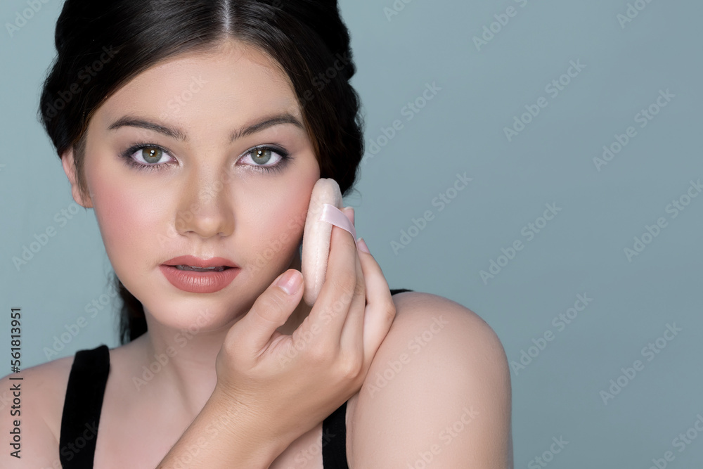 Facial cosmetic makeup concept. Closeup portrait of young charming girl applying dry powder foundati