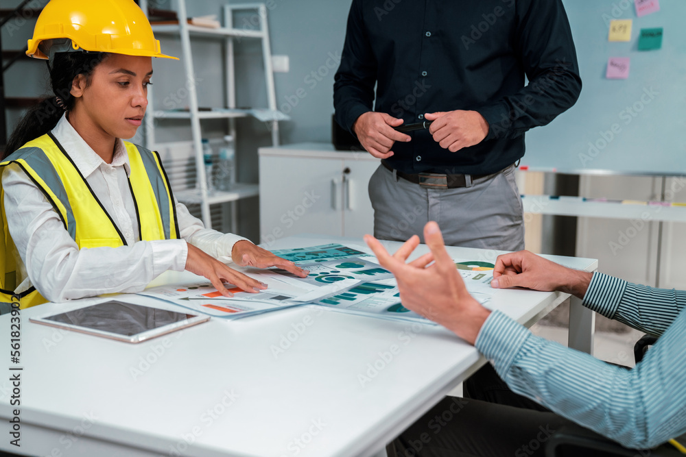 Engineers and competent employer discussing plans and blueprints together with tablet in the office.