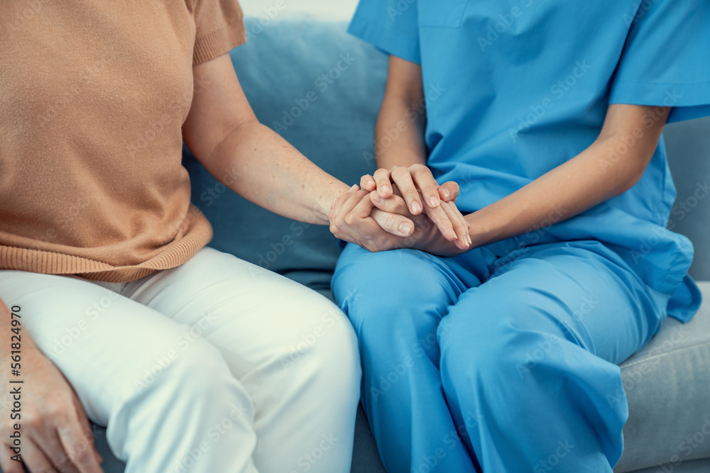 A contented senior woman visited by her personal caregiver and hold each others hands.