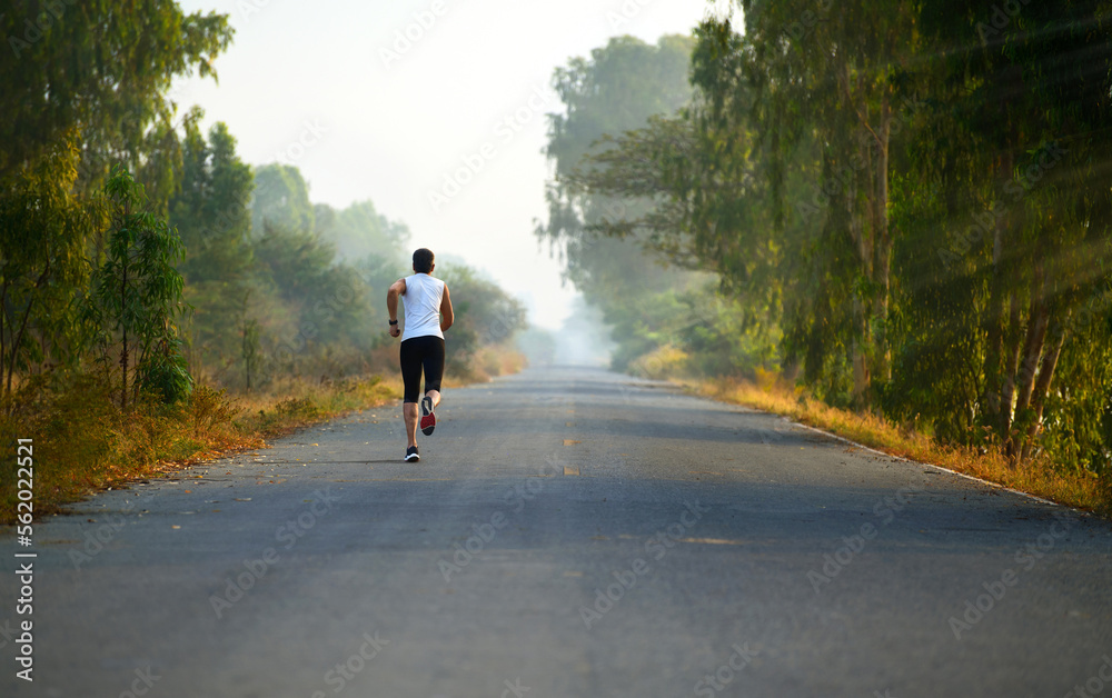 A man jogging alone through the road in morning.