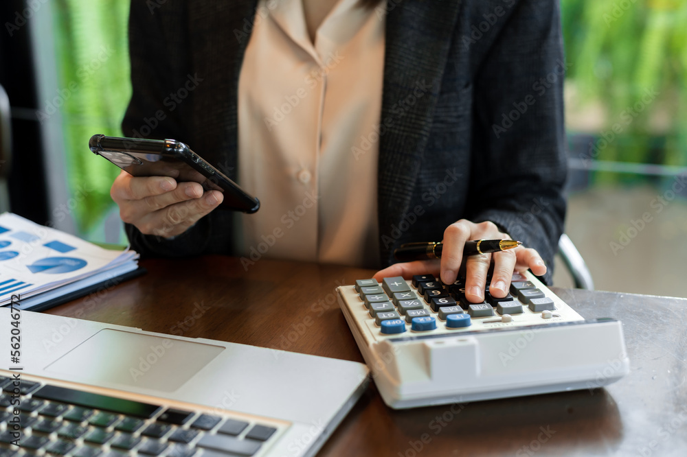 Businesswoman hands working with finances about cost and calculator and laptop with tablet, smartpho