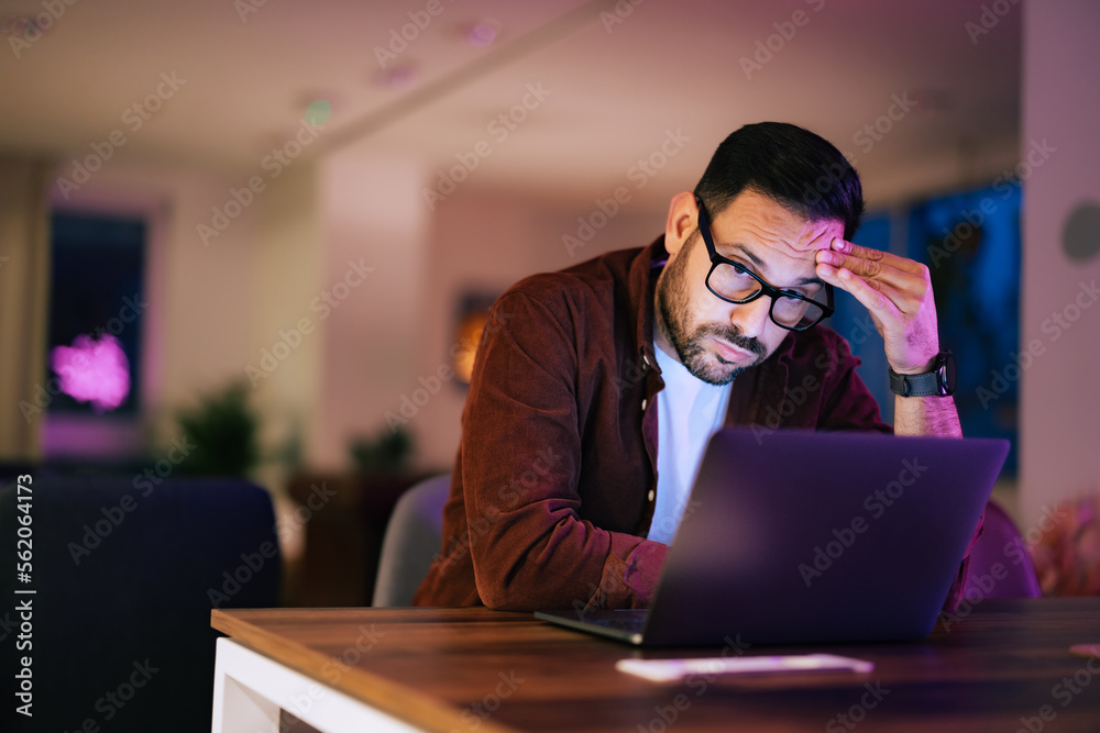 Businessman working late at night at his desk, using a laptop.