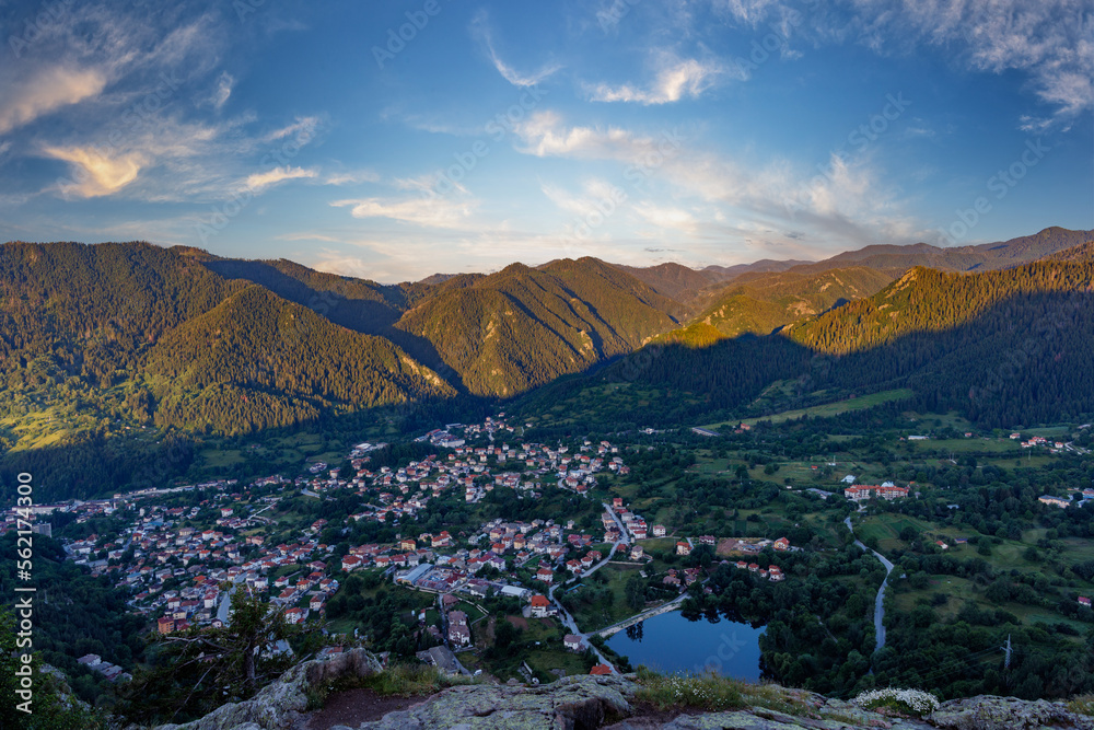 View from rock to town of Smolyan with meadows for cattle walking and houses between mountain range 