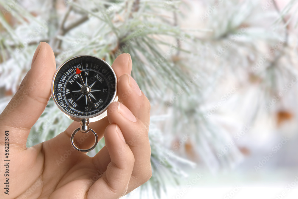 Human hand with compass in winter forest