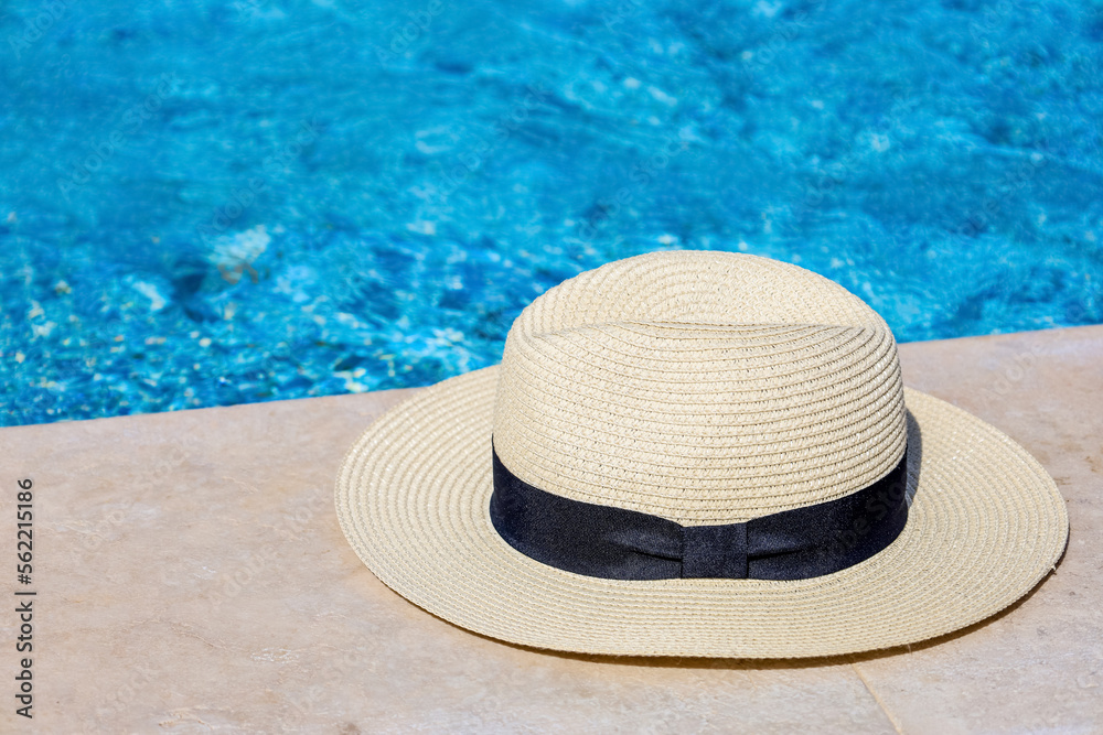 Summer hat on edge of swimming pool, closeup