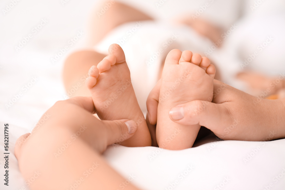 Mother massaging her babys feet in bedroom, closeup