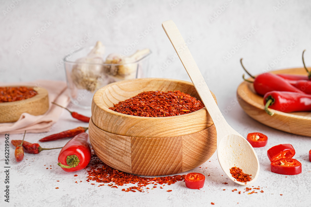 Wooden bowl of chipotle chili flakes on light background