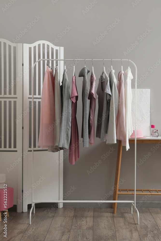 Rack with stylish female clothes in interior of room