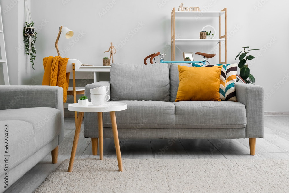 Interior of living room with sofas, coffee table and bicycle near grey wall