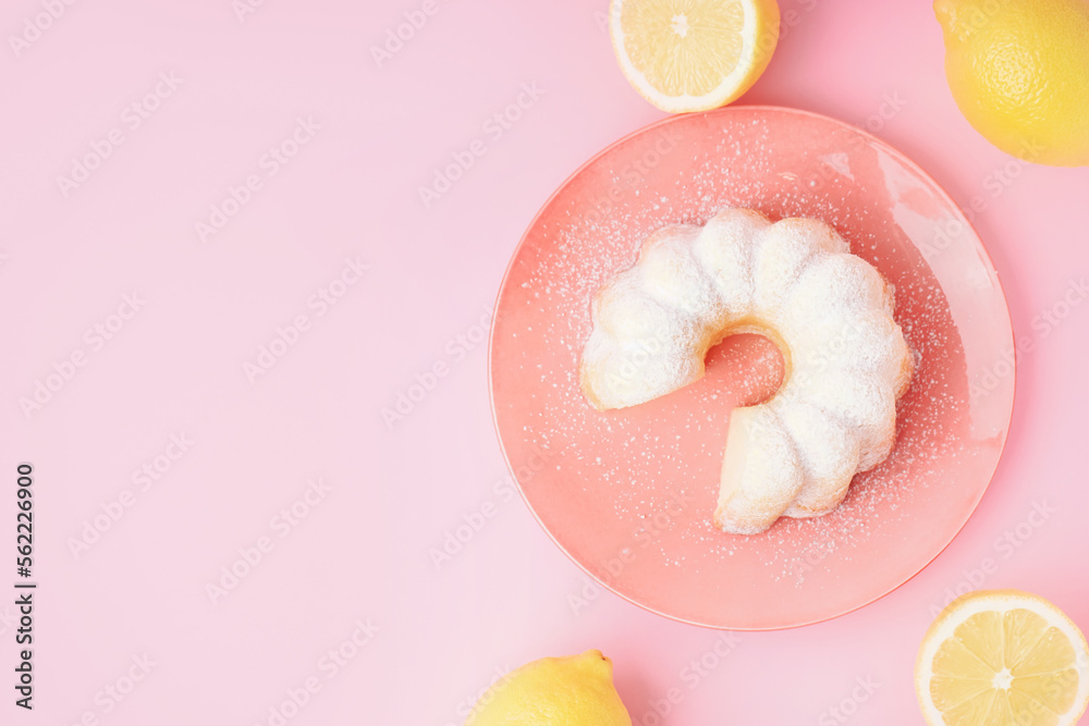 Plate with delicious cake and lemons on pink background