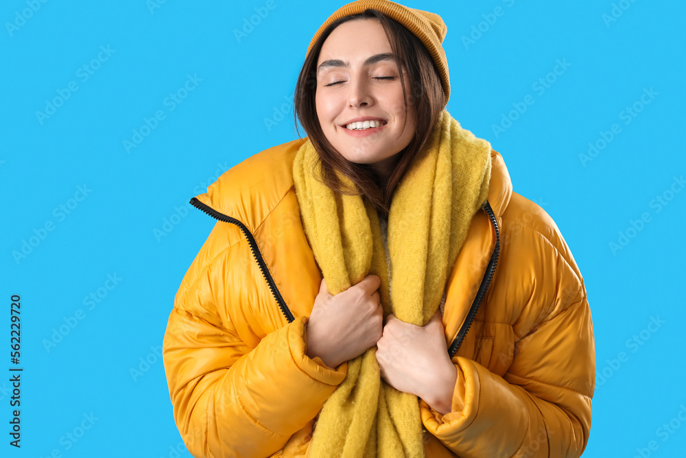 Young woman in winter clothes on blue background