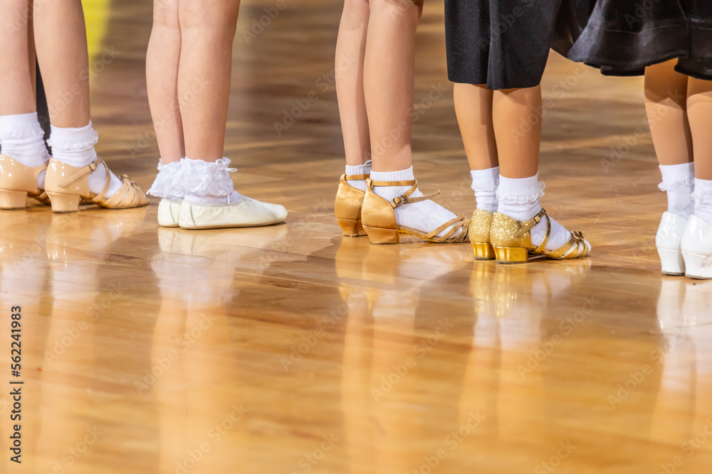 Legs of small girls in ballroom dance shoes.