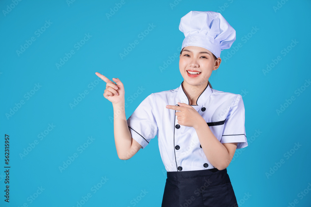 Portrait of young Asian female chef on background