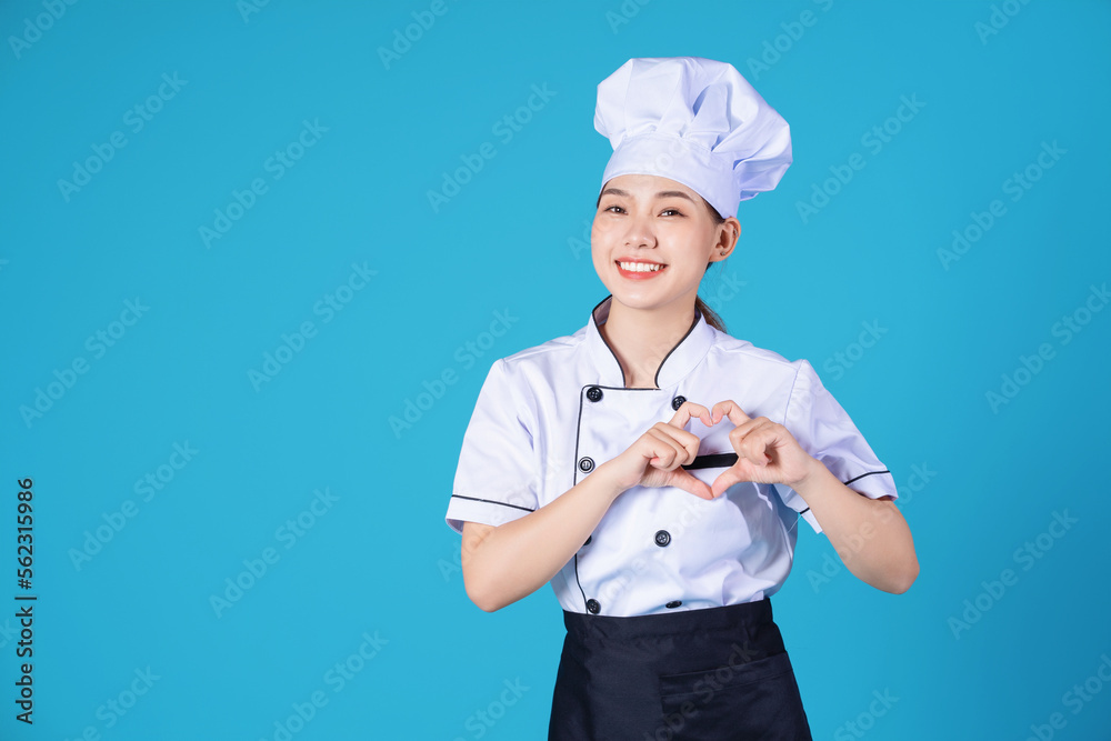 Portrait of young Asian female chef on background