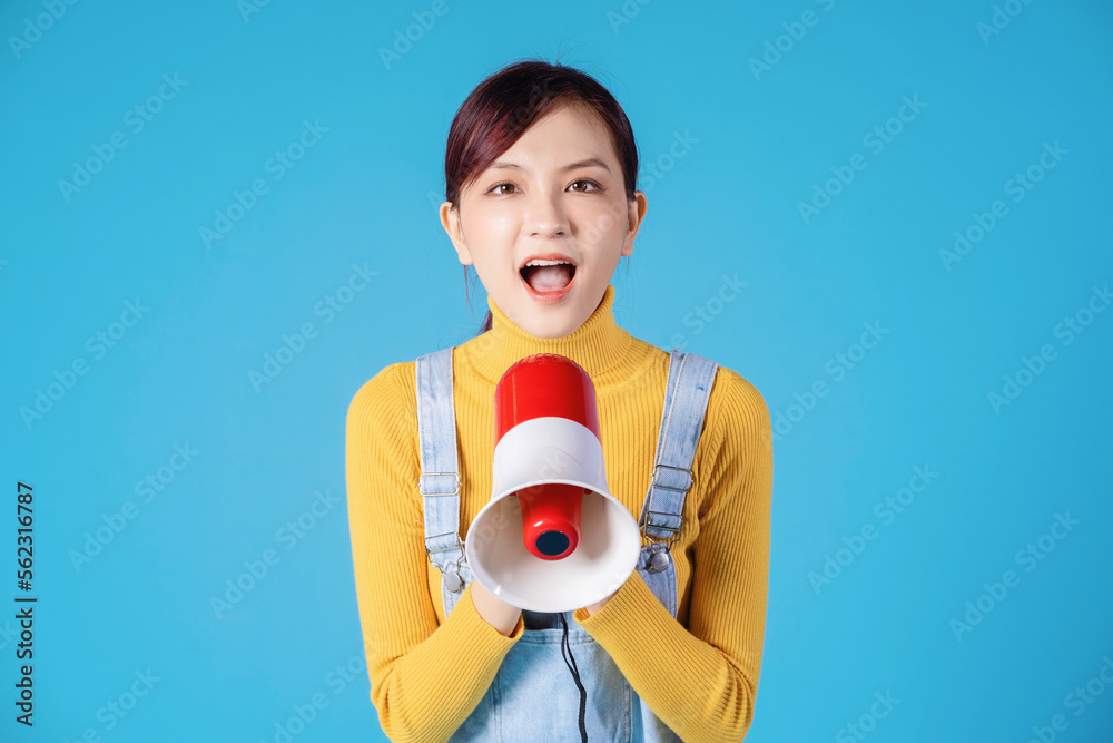 Young Asian girl using megaphone on blue background