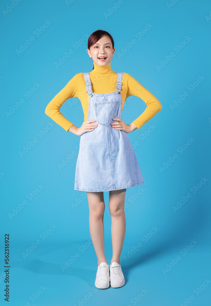 Full length photo of young Asian girl standing on blue background