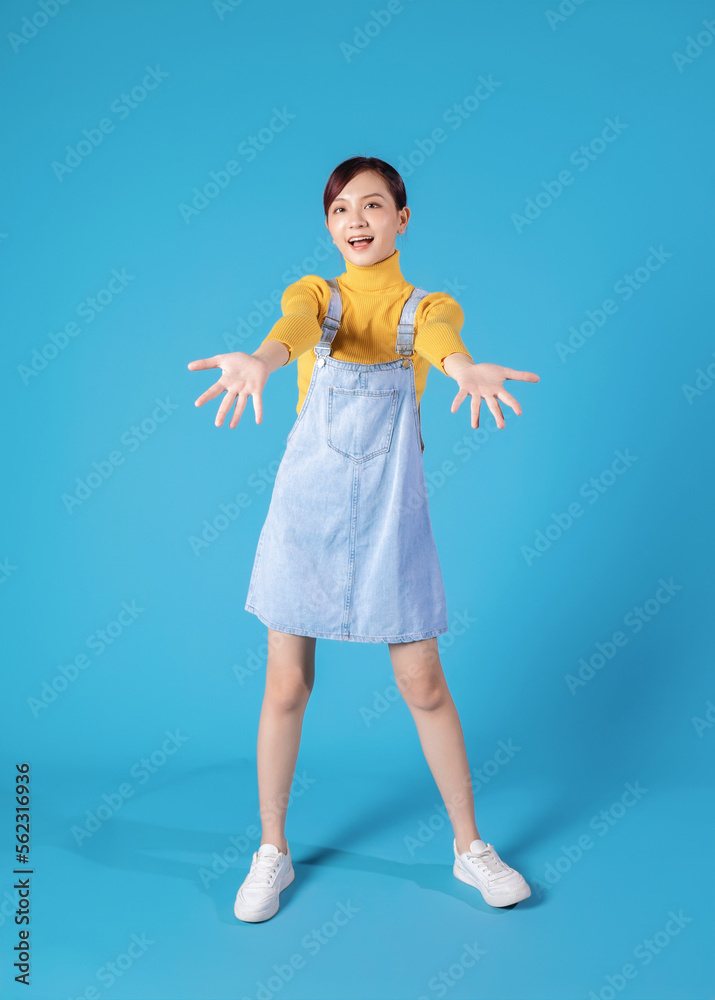 Full length photo of young Asian girl standing on blue background