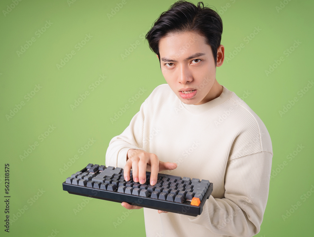 Image of young Asian angry man holding keyboard