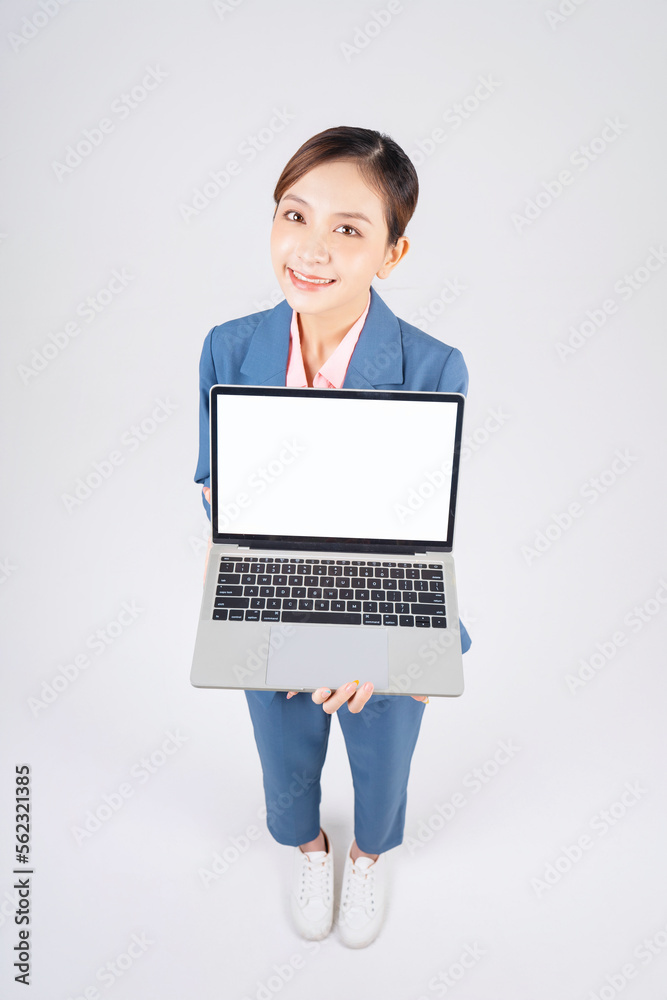 Full length photo of young Asian businesswoman using laptop