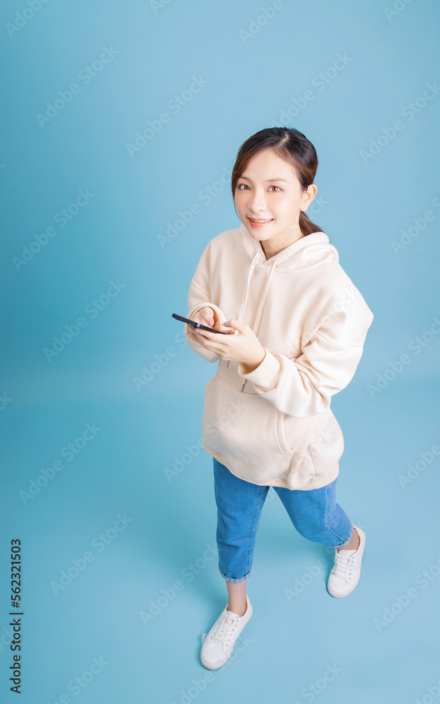 Full length image of young Asian girl using smartphone