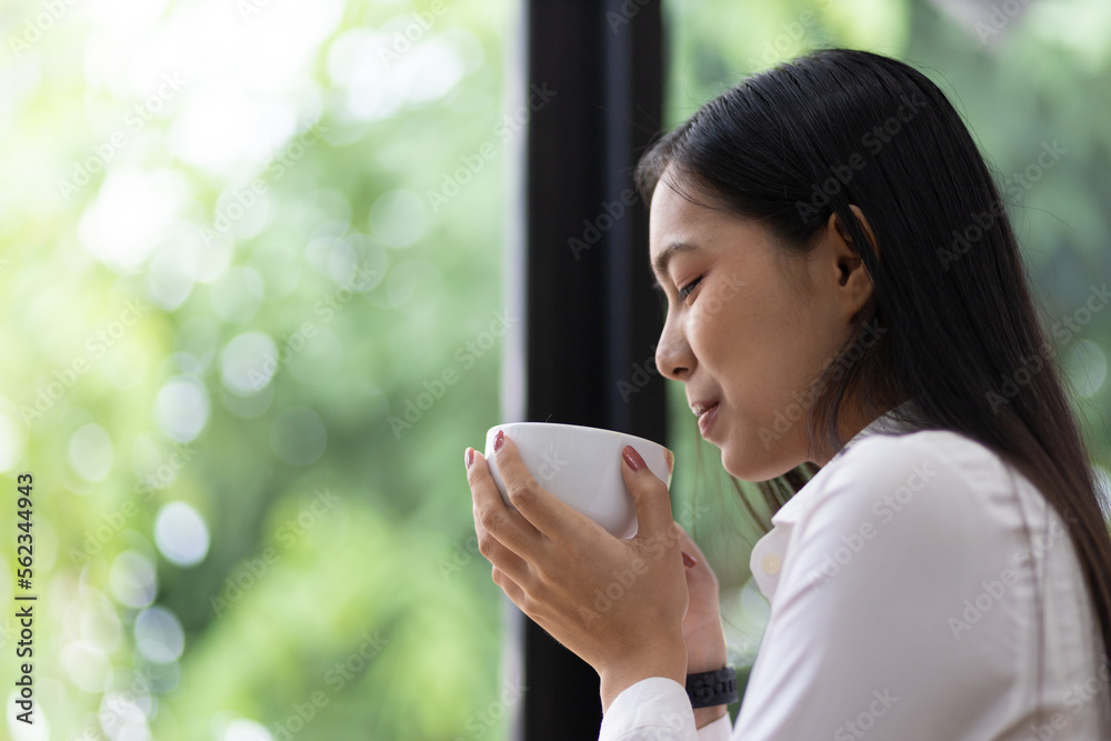 快乐的亚洲女人早上喝咖啡。