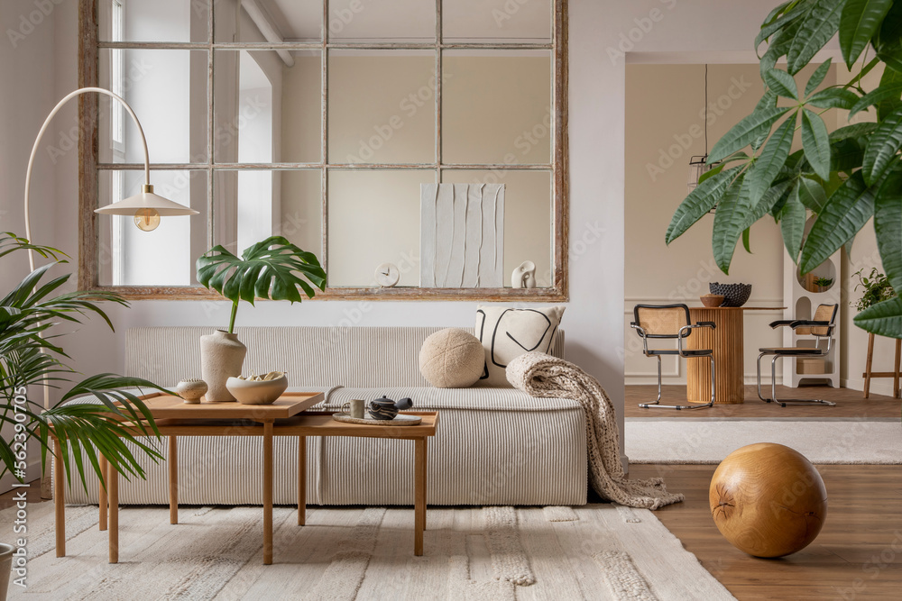 Open space interior with modular sofa, wooden coffee table, big window, beige rug, braided plaid, pi