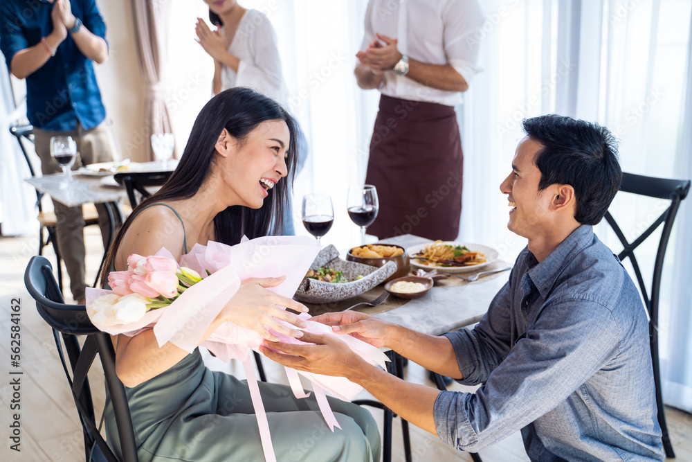 Asian romantic man making surprise proposal of marriage to girlfriend.