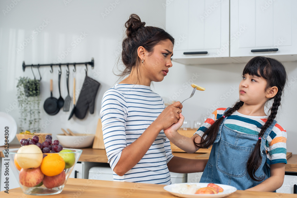 Asian mother teaching and motivate young girl child eat healthy fruit. 