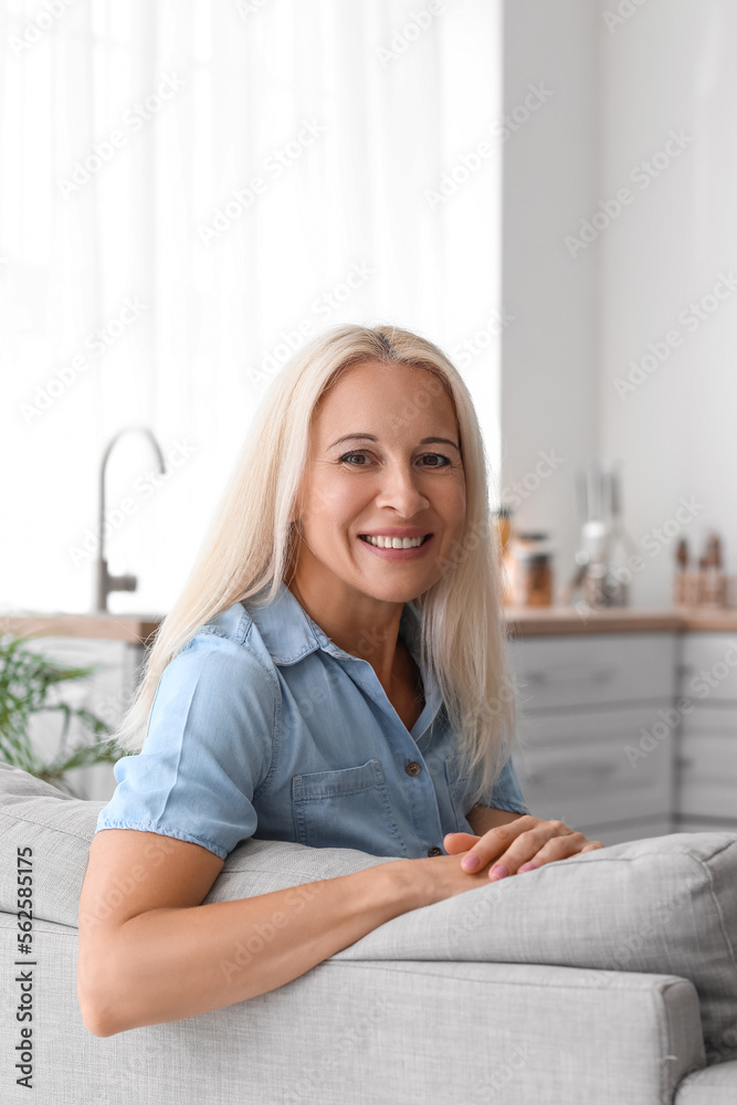 Mature woman sitting on sofa in kitchen