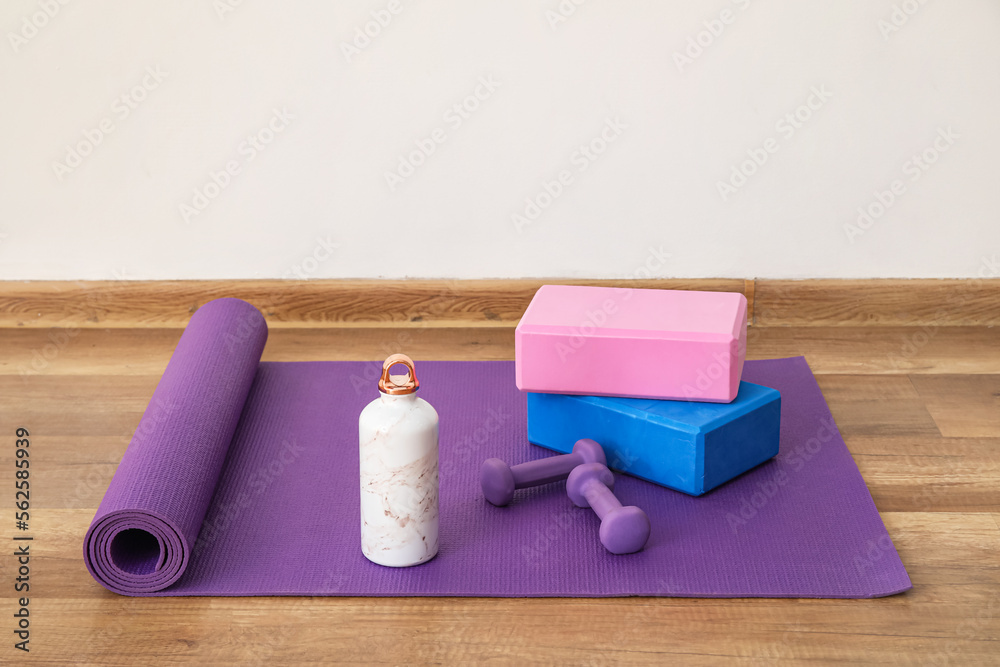 Sports water bottle with equipment on mat near light wall