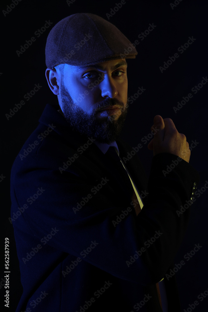 Silhouette of young bearded man in cap on dark background