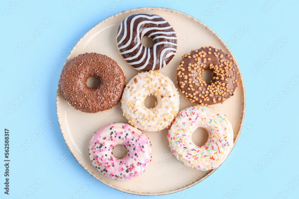 Plate of sweet donuts on color background