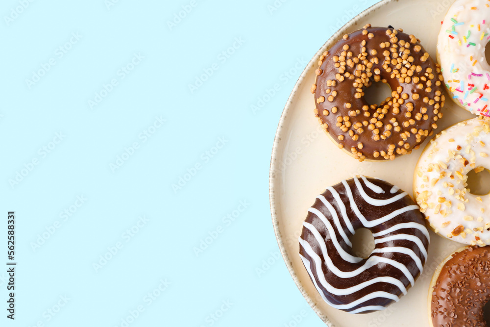 Plate of sweet donuts on color background