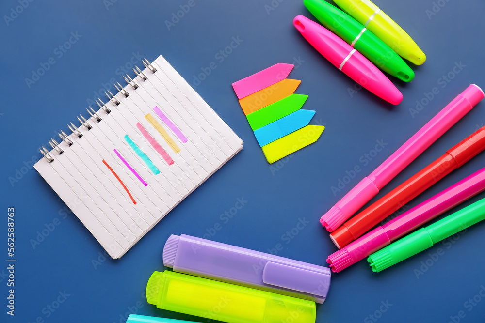 Different markers, sticky notes and notebook on color background