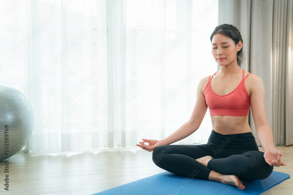 Asian woman exercise and stretching in her bed room, her try to make slim by take Yog