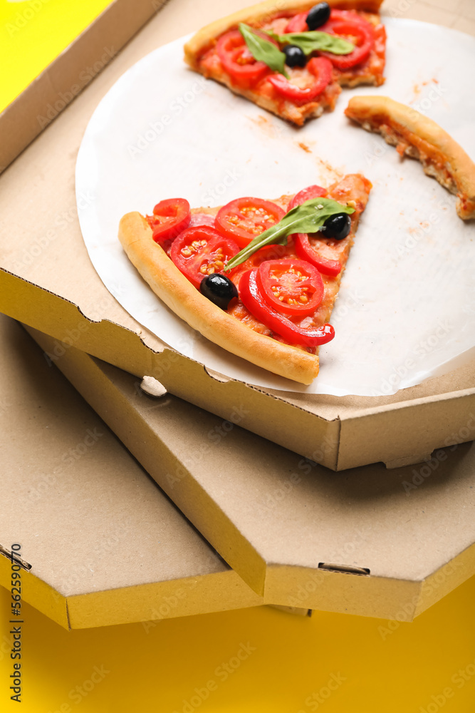 Stack of cardboard boxes with pizza leftovers on yellow background, closeup