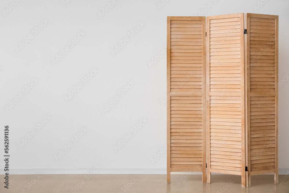 Wooden folding screen near white wall