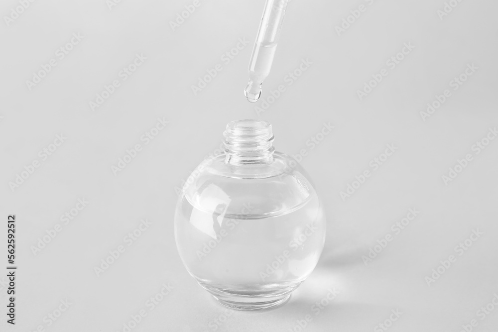 Dripping of serum from pipette into bottle on light background