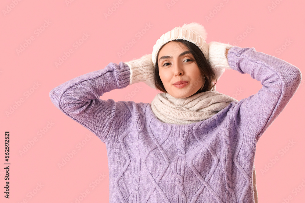 Frozen young woman in winter clothes on pink background