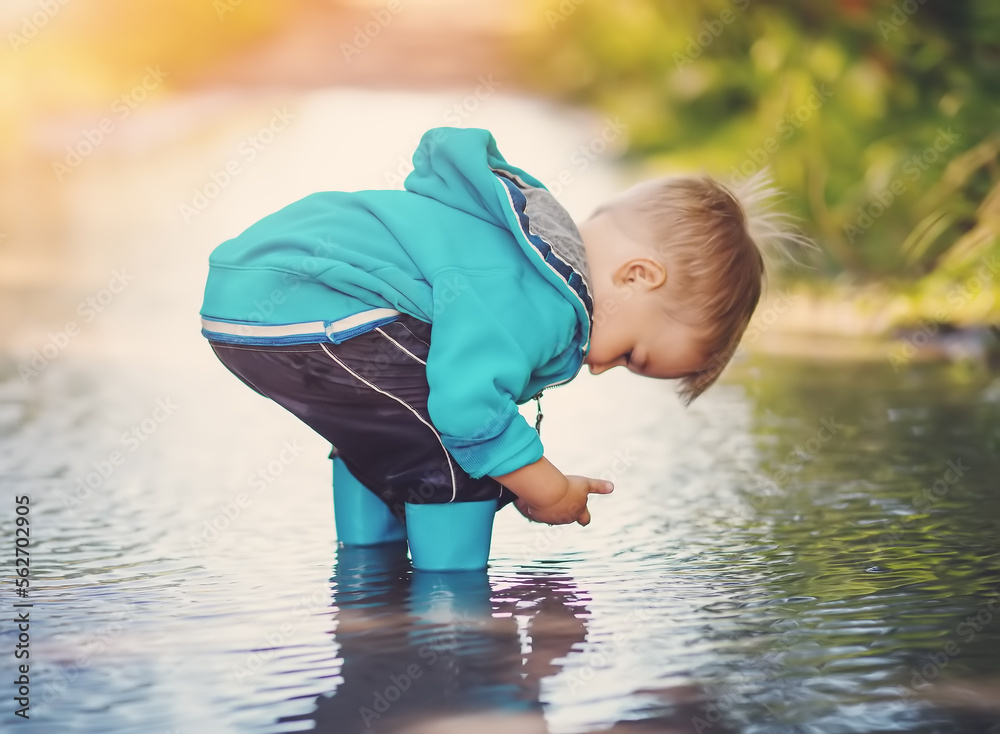 可爱的小孩站在水坑里玩雨水。