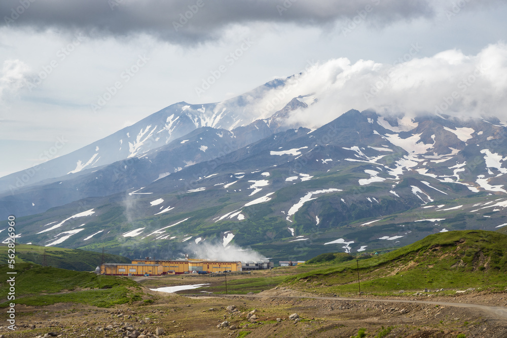 Geothermal power plant in a mountain valley. View of the buildings of the power station and the volc