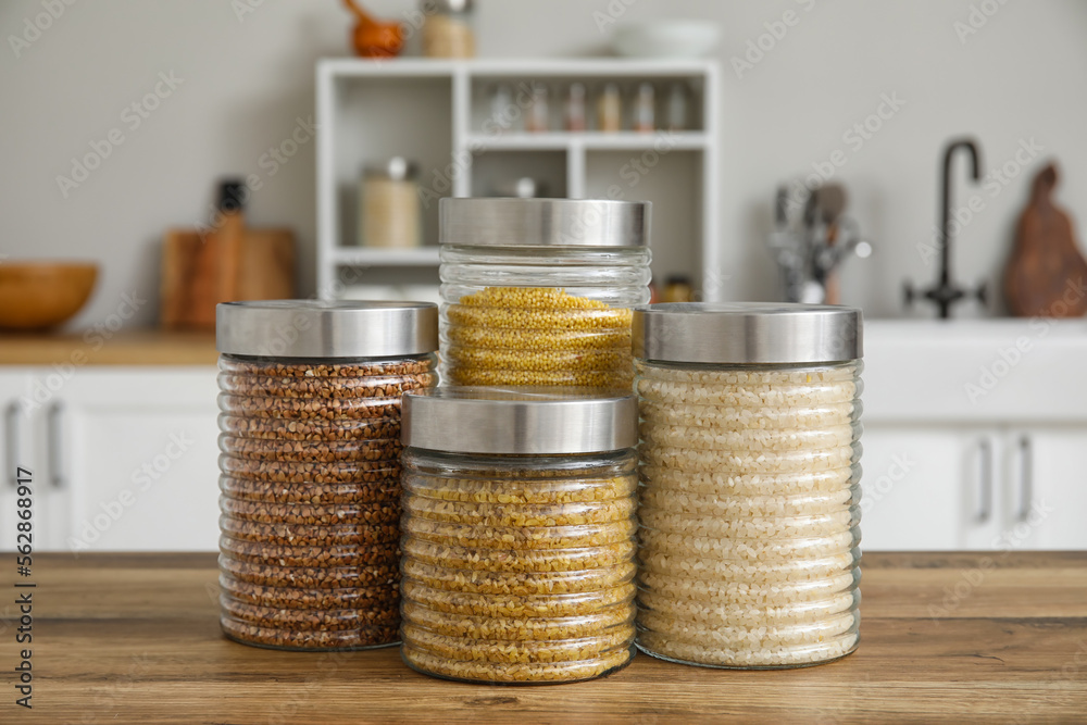 Jars with cereals on wooden table in kitchen