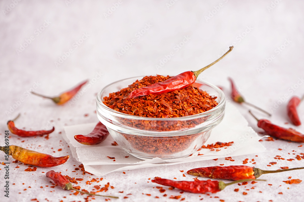 Bowl of chipotle chili flakes and dried jalapeno peppers on light background